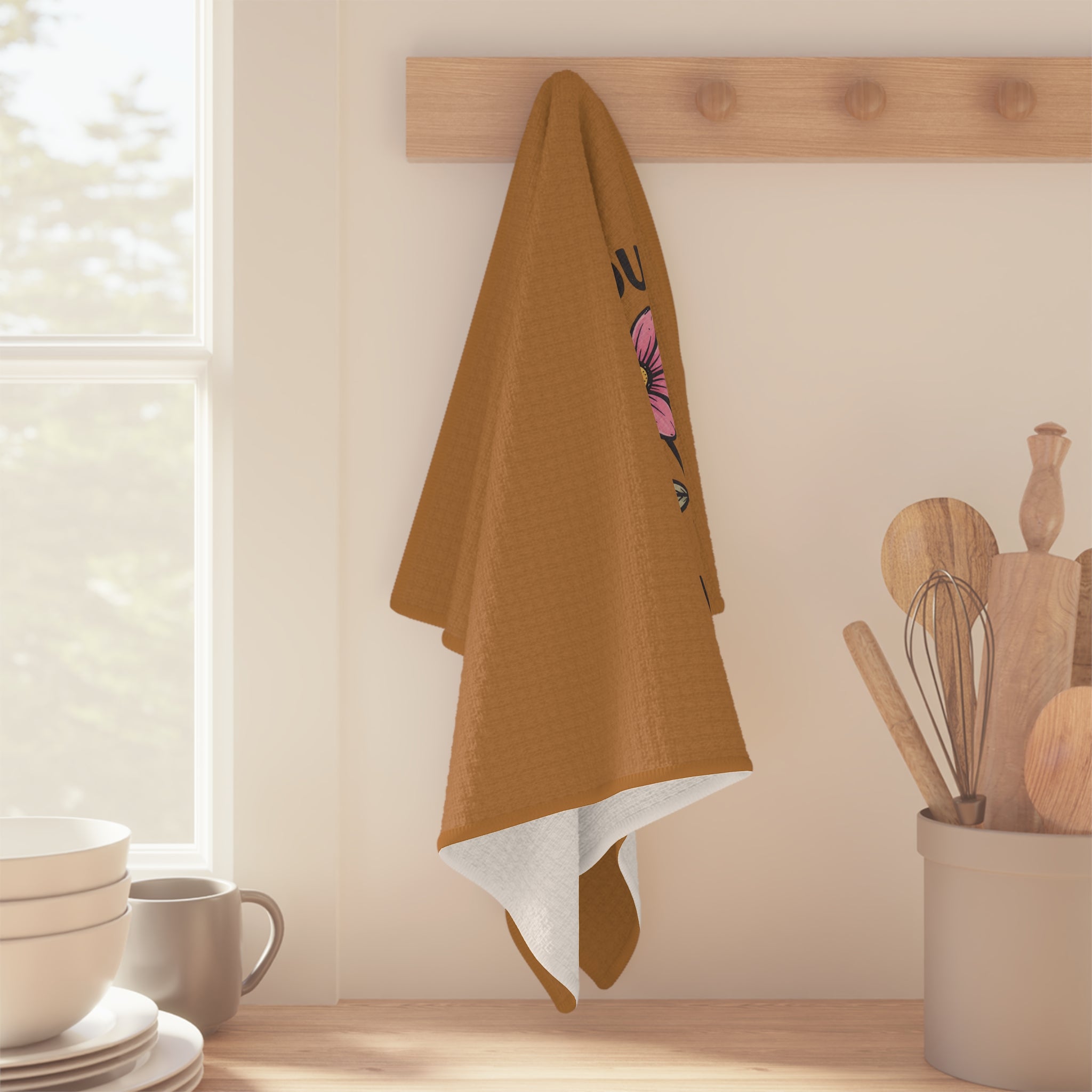 Brown towel with a butterfly design hanging on a wooden rack in a kitchen.