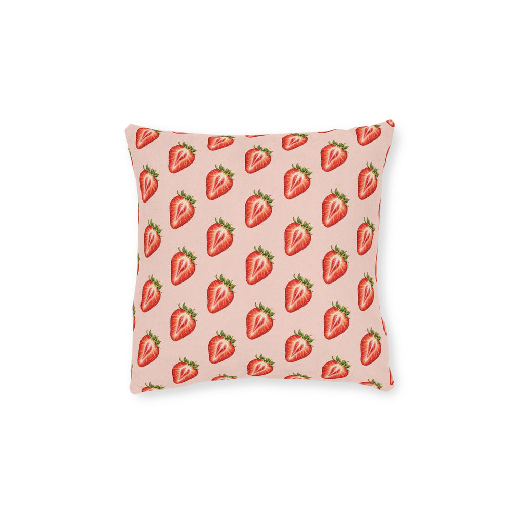 A square throw pillow featuring a repeating pattern of red strawberries with green tops on a light pink background, shown against a plain white studio backdrop.